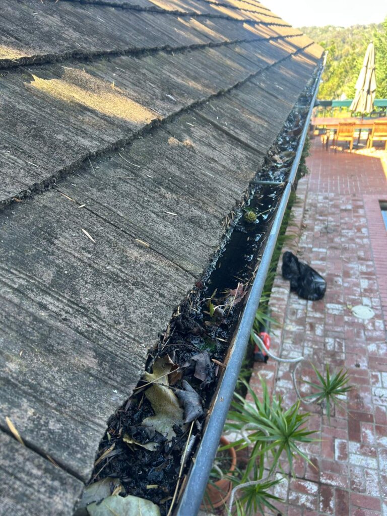 Gutter cleaning in progress below a shake roof