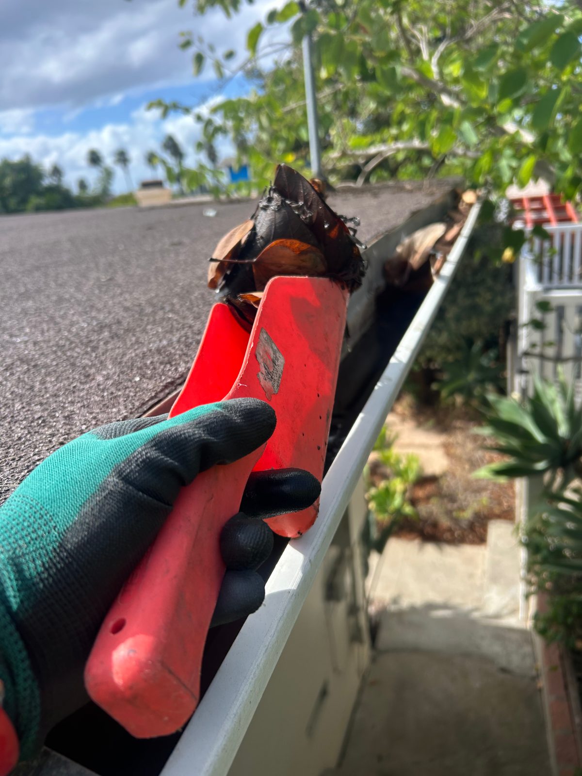 Gutter cleaning Same Day Pressure Wash technician removing packed debris from a gutter by hand