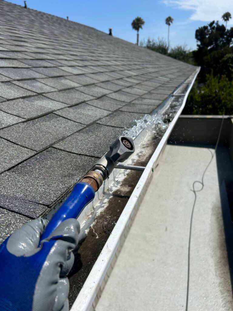 Gutter cleaning along a shingle roof