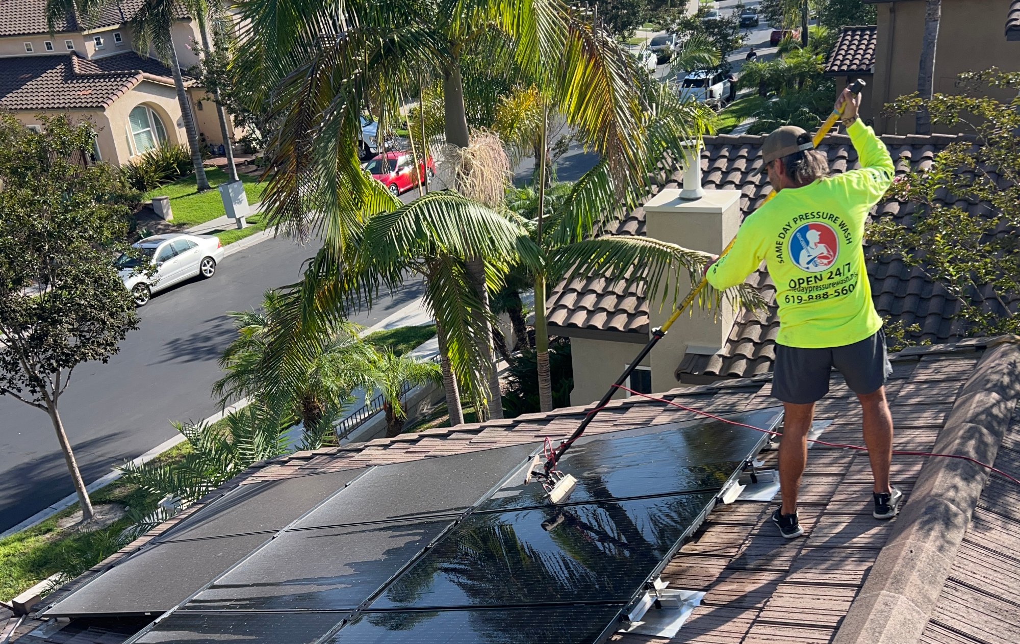 solar-panel-cleaning-san-diego-crew Same Day Pressure Wash technician cleaning solar panels with a soft brush on a San Diego tile roof